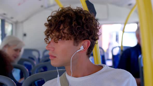 Male commuter listening music on earphones while travelling in bus 4k alt
