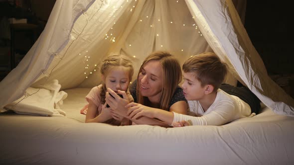Happy Mom with Two Children Looking Through Photos on Her Phone