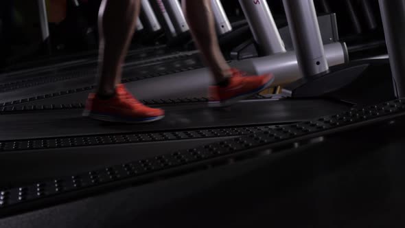 Men's Feet in Red Sneakers on the Treadmill