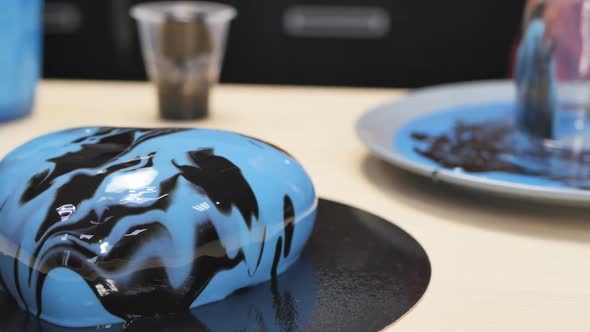 The Pastry Chef's Hands Pushed Aside a Blue Mousse Cake in Mirrored Glaze