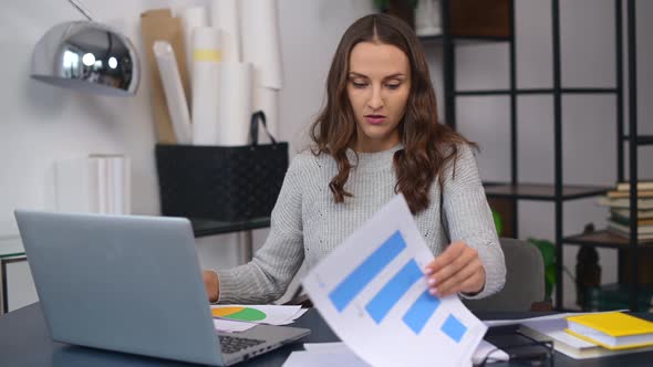 Female Employee Looking Through Workpapers on the Table Trying to Find Needed alt