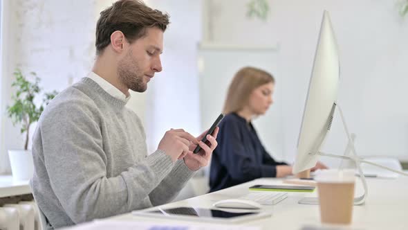 Serious Creative Professional Using Smartphone in Office alt