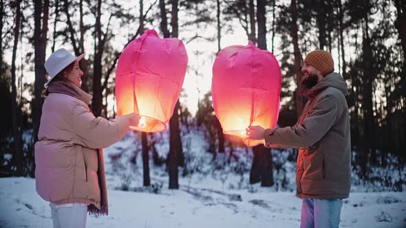 Couple Light Sky Lantern and Hug in the Woods in Winter Celebrating Valentines
