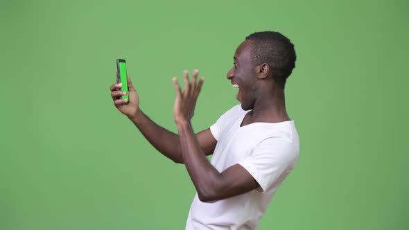 Young African Man Video Calling with Phone Against Green Background alt