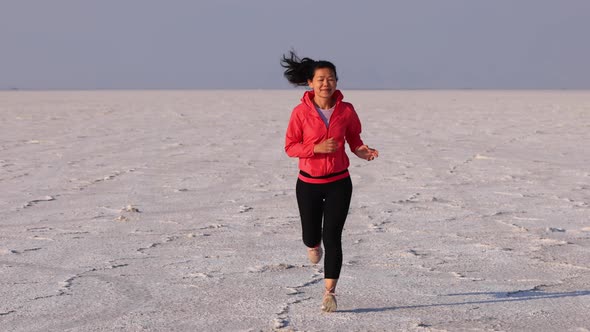 Asian woman jogging across the Bonneville Salt Flats flats alt