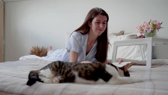 A Woman Strokes a Cat While Lying on the Bed
