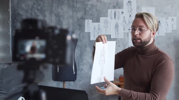 Young fashion blogger is recording video blog about design of clothes using camera. alt