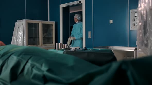 Two Professional Surgeons in Uniforms Gloves Masks and Hats Enter the Operating Room alt