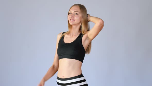 Happy fit girl with sportswear smiling and posing over white studio background.	