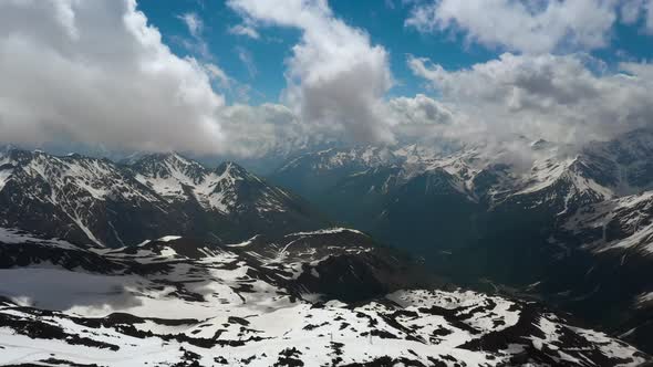 Air Flight Through Mountain Clouds Over Beautiful Snowcapped Peaks of Mountains and Glaciers alt