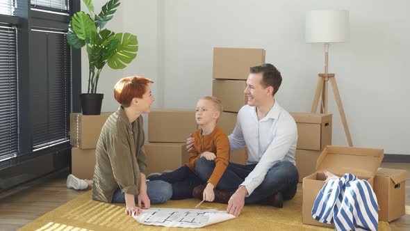 Relaxed Family With Child Boy Sit On Floor Talking Planning Their Home Interior Moving Into New