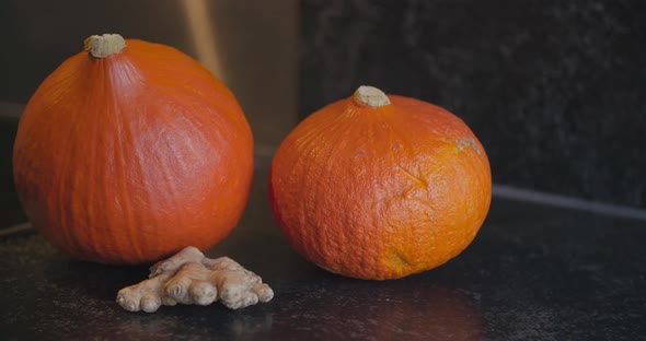 two orange pumpkins and ginger ready to be used for soup ingredients or halloween decoration alt