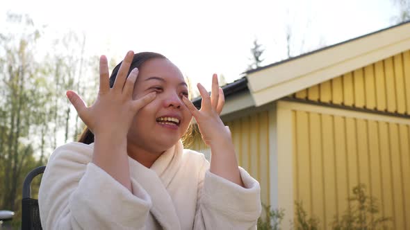 close up Asian woman sitting on a chair outside home and laughing with friend in the morning alt