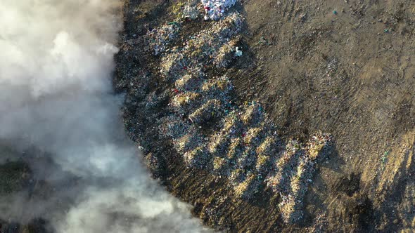 Aerial view of burning garbage pile in trash dump or landfill alt