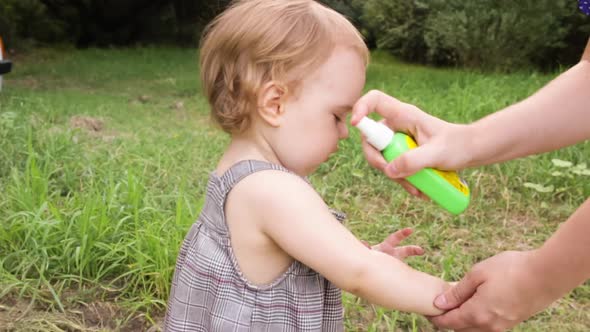 Mom Spraying Repellent to Protect Child Infant Toddler From Mosquitoes alt