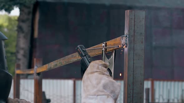 Slow Motion Closeup Builder Welds Plank to Fence at House alt