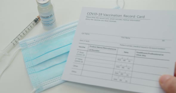 Medical Mask and COVID19 Vaccine Doctor Hand Put Vaccination Record Card alt
