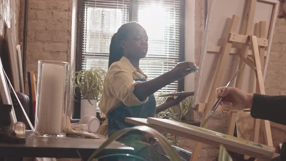 Black Woman Painting in Bright Studio alt