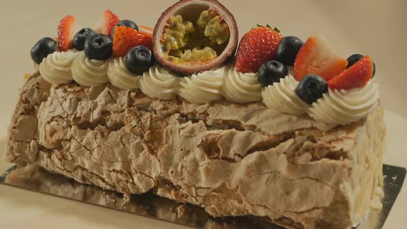 Dessert Roll of Meringue with Butter Cream Decorated with Fruits and Berries Rotates Slowly alt