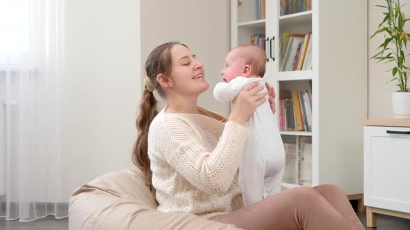 Smiling Yougn Mother Sitting in Beanbag and Holding Her Little Baby Son alt