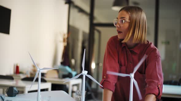 Young woman speaking during meeting with wind wheels at office