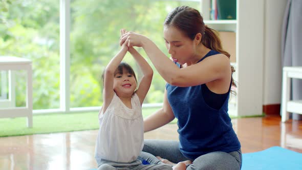 Little daughter try to learning yoga with young mother