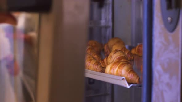 The Pastry Chef Opens the Oven with Freshly Baked Croissants. Fresh Pastries. alt