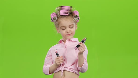 Little Girl in Curlers Chooses the Most Beautiful Lipstick. Green Screen alt