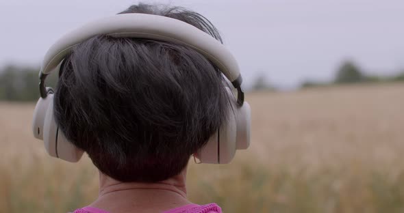 Closeup Portrait of Woman's Face 60 Years Old Meditates in Nature in Headphones alt