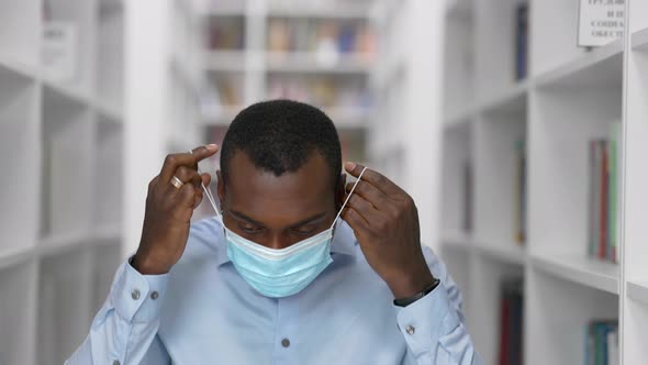 University Library: African American Man in a Mask During Quarantine Covid-19 Prepares for the Exam alt