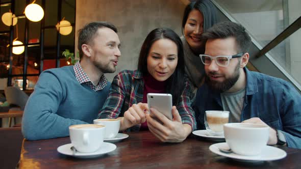 Asian and Caucasian Friends Using Smartphone Talking Smiling Having Fun in Cafe alt