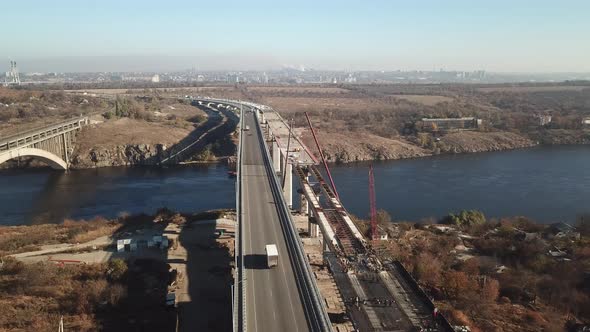 Construction of a bridge across the river. Heavy traffic on the bridge. Drone aerial high angle view alt