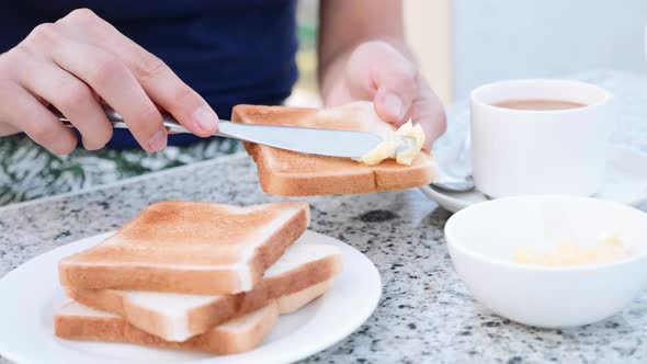 Woman is Buttering Toast Table Knife with Butter Making Sandwich for Breakfast alt