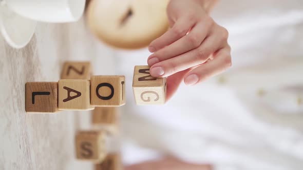 Girl Without Face Adds Word Goal. Human Hand Puts Wooden Blocks One On Top Of Other, They Fall alt