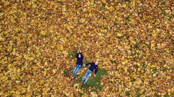 Aerial viev Happy Children Lying On Autumn Fallen Leaves in the Park