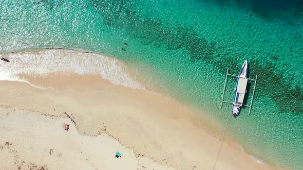 Long boat floating over tranquil crystal emerald sea water near shore of tropical island waiting for alt