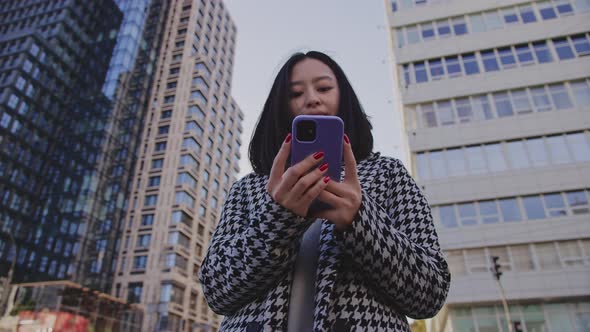 Medium Shot of a 20s Asian Woman with a Smartphone in the City Downtown alt