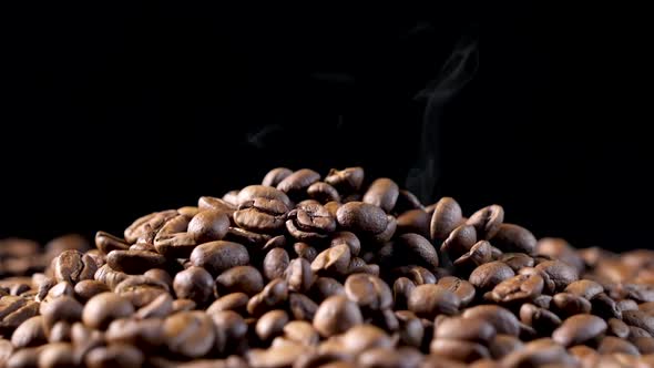 Smoke over a roasted coffee beans on the oven. Smooth motion of arabica coffee seeds. alt