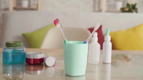 Close Up Woman's Hand Puts a Toothbrush with Blood in a Cup. alt