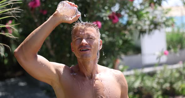 Handsome Man Douses Himself with Cold Water From Bottle in Summer alt