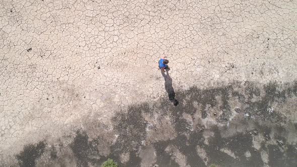 Top down view of woman walking across dry cracked desert viewing shadow alt