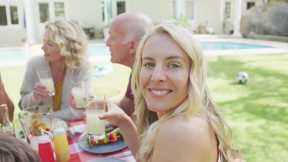 Portrait of happy caucasian woman having dinner with family in garden alt