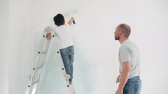 Caucasian Man and Boy Paint the Wall Father Teaches Son to Paint Standing on the Stairs Father and