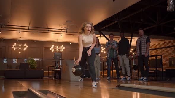 A Young Woman in Bowling Throws a Ball on the Track and Knocks Out a Shot in Slow Motion and Jumps alt