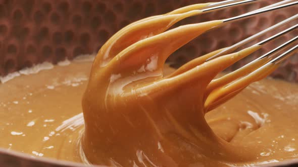 Melted caramel dripping from whisk, closeup food shot. 