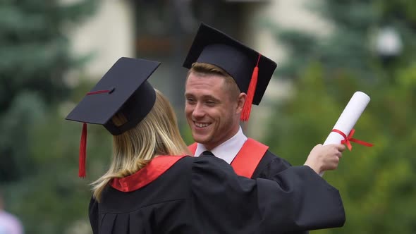 Male and Female Graduates in Academic Caps Hugging, Friends Sorry to Say Goodbye alt