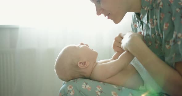 Young Mother is Playing with Her Newborn Baby
