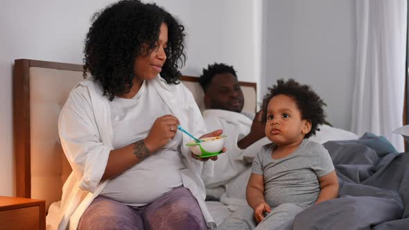 Hyperactive Toddler Boy Sitting on Bed with Woman Feeding Child Talking alt