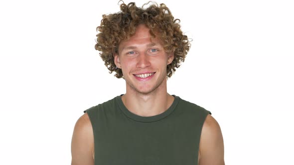 Caucasian Curly Guy in Green Muscle Shirt Nodding in Agreement Looking on Camera Smiling Over White alt