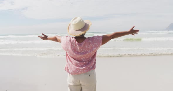 Mixed race senior woman spinning with open hands at the beach alt